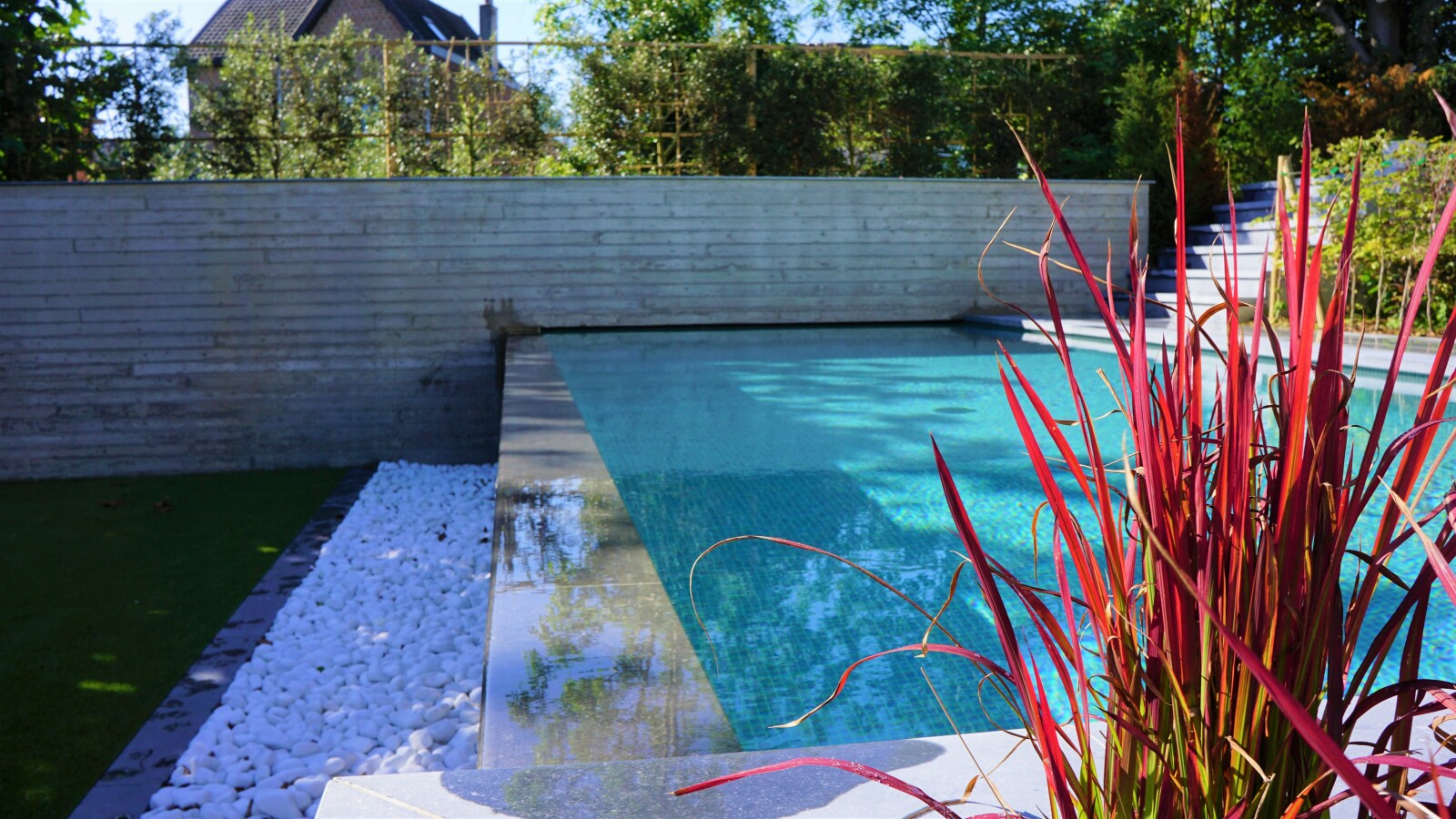Overloopzwembad over zijwand in een tuin op 3 niveaus.